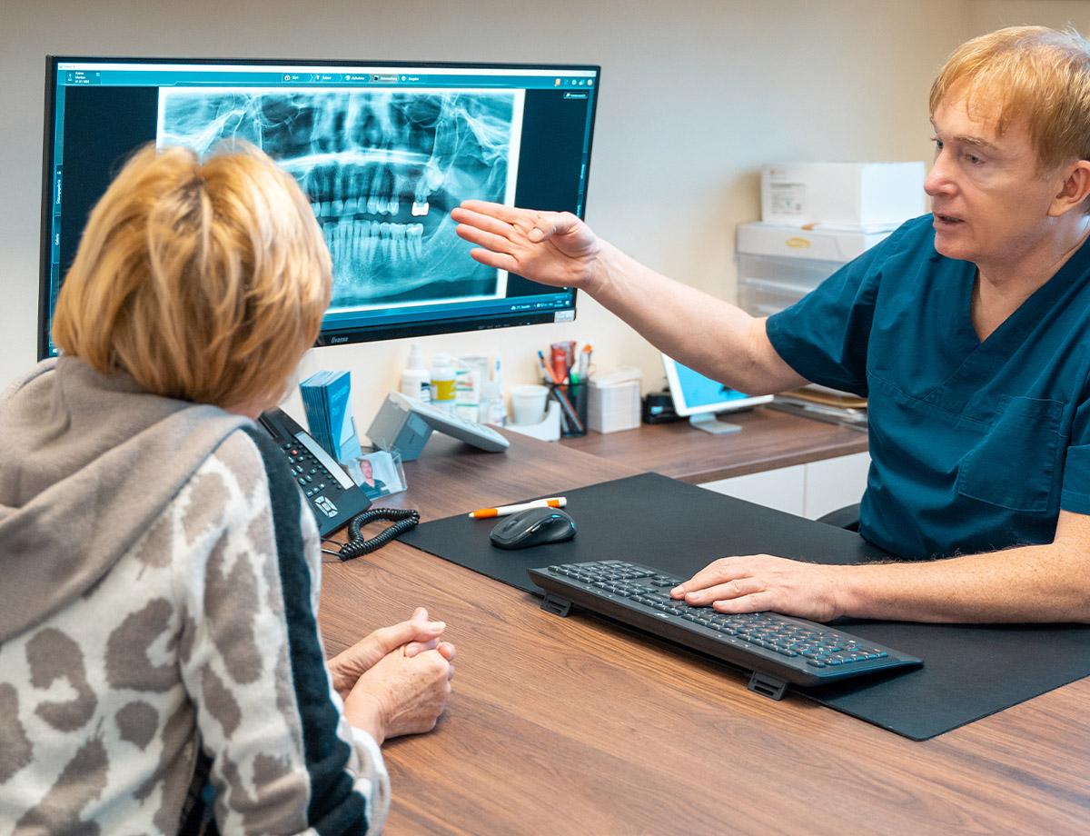 Patientenberatung mit viel Einfühlungsvermögen für ein Implantat durch Dr. Markus Keiner am PC in der Zahnarztpraxis